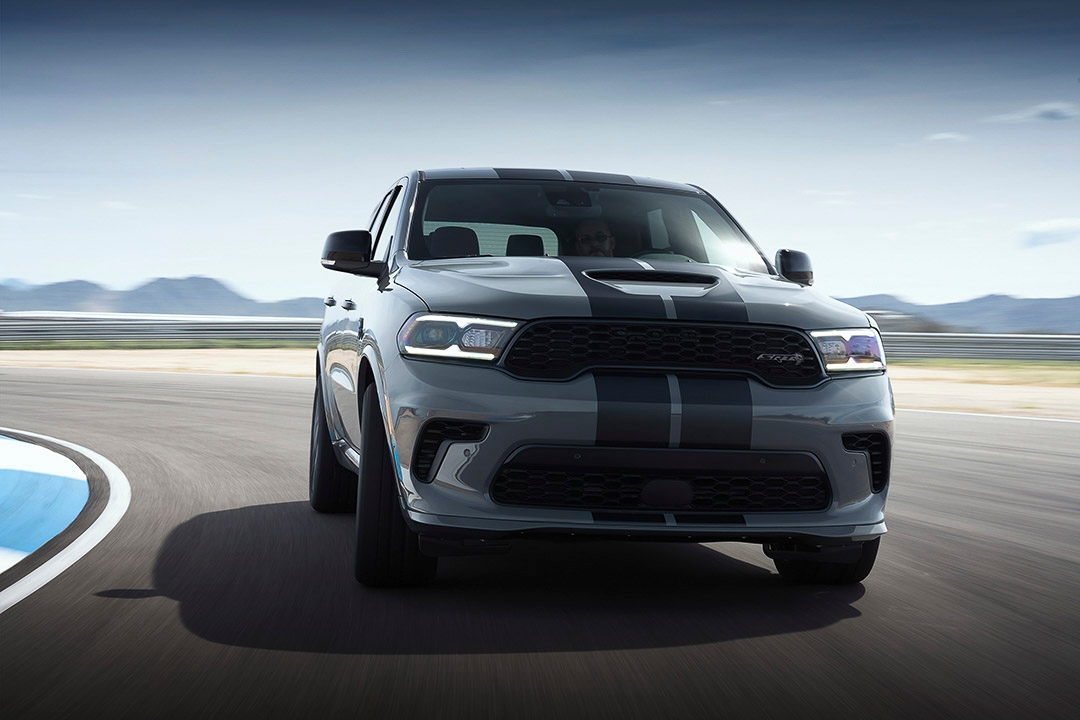 Dodge Durango SRT Hellcat 2021 gris sur circuit, vue avant dynamique avec bandes noires sur le capot.