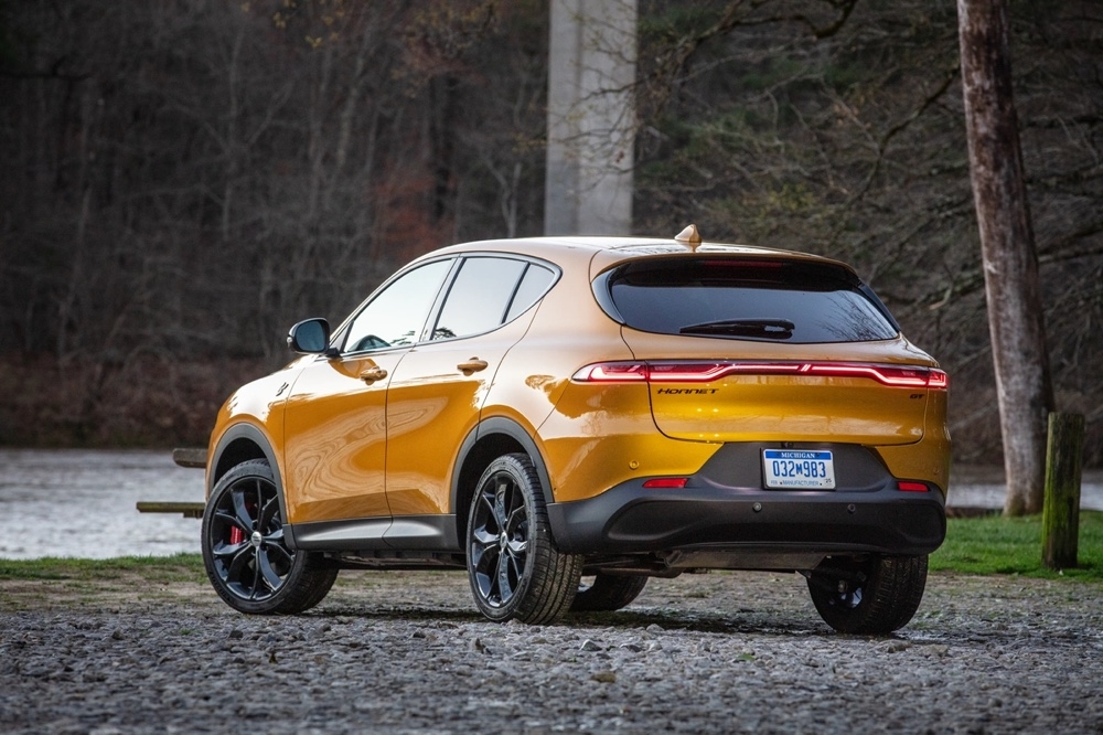 Vue arrière du Dodge Hornet GT 2025 jaune stationné en nature avec feux arrière allumés et jantes noires sport.
