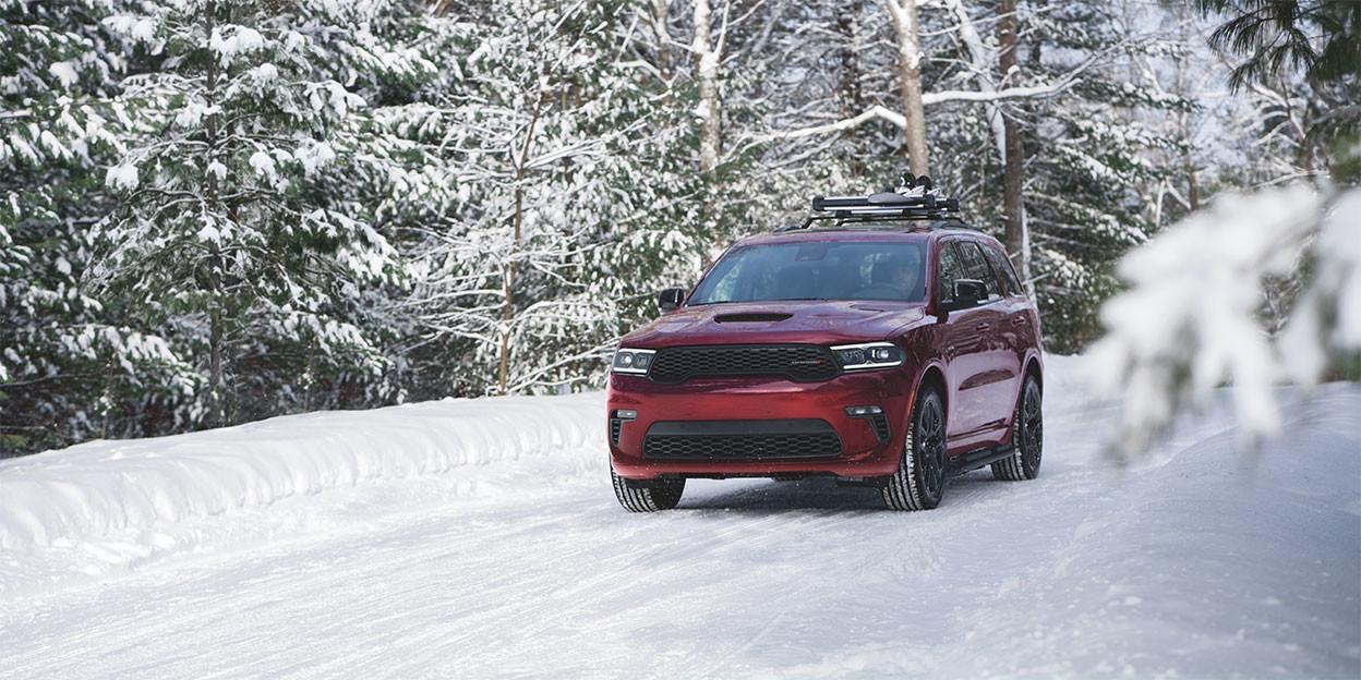 Dodge Durango 2025 stationné devant une chaîne de montagnes au coucher du soleil, en vue trois quarts avant.