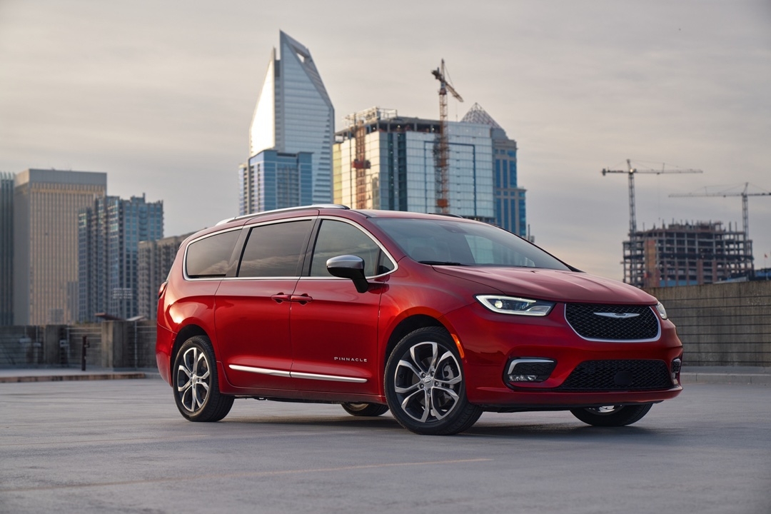 Chrysler Pacifica 2025 version Pinnacle rouge garée sur un toit urbain, avec des gratte-ciels en arrière-plan, vue trois quarts avant.