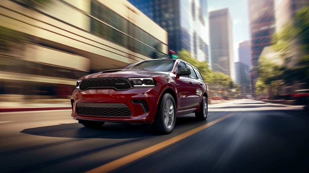 Dodge Durango rouge 2025 en pleine accélération sur une avenue bordée de gratte-ciels en plein jour.