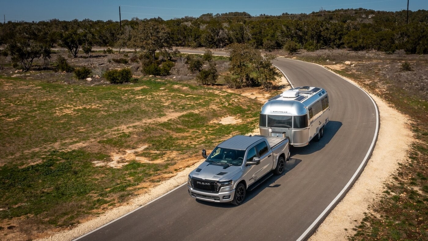 Le RAM 1500 2025 remorquant une roulotte sur une route.