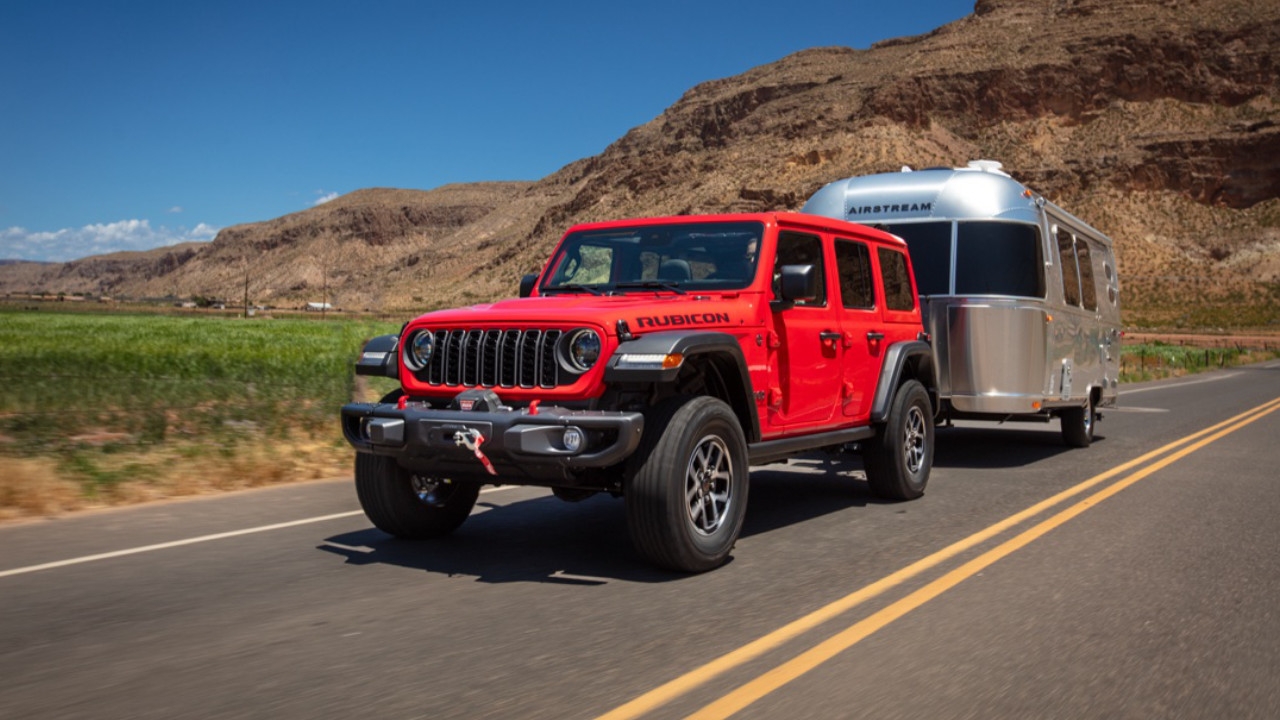 vue latérale avant d'un Jeep Wrangler 2025 qui remorque une roulotte