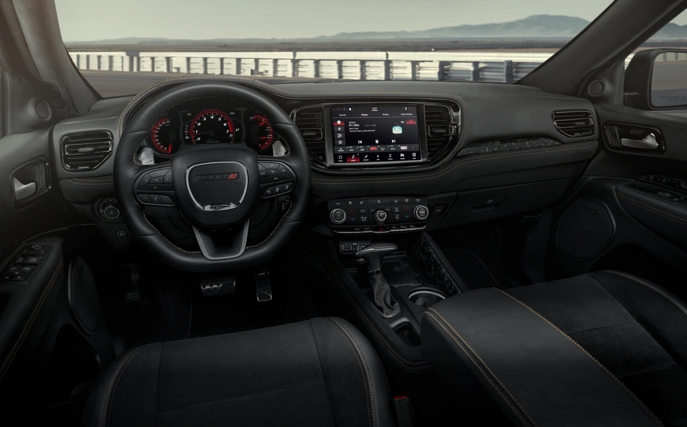 Vue intérieure du Dodge Durango 2025 montrant le tableau de bord, l’écran Uconnect 5 et les sièges en cuir noir surpiqués.