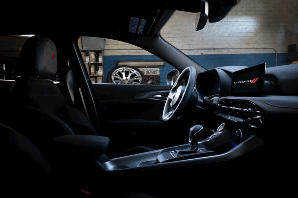 Intérieur sombre du Dodge Hornet 2025 avec tableau de bord numérique et écran tactile allumé.