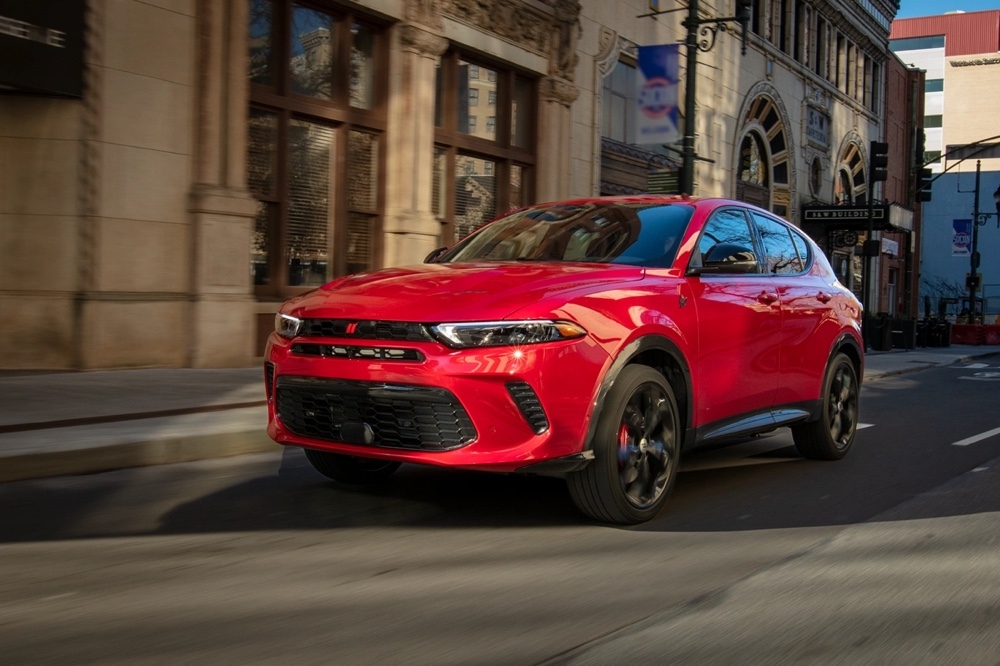 Dodge Hornet GT rouge 2025 en mouvement sur une rue urbaine bordée d’édifices historiques.