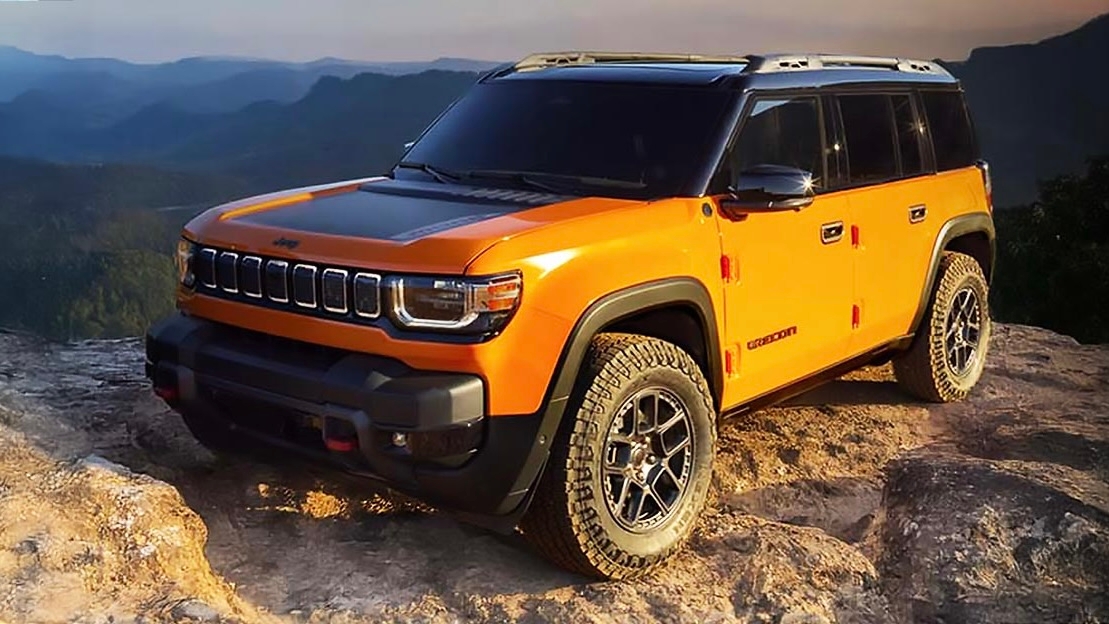 Jeep Recon EV 2026 orange stationné en haut d’un rocher au coucher du soleil, avec vue panoramique sur les montagnes.