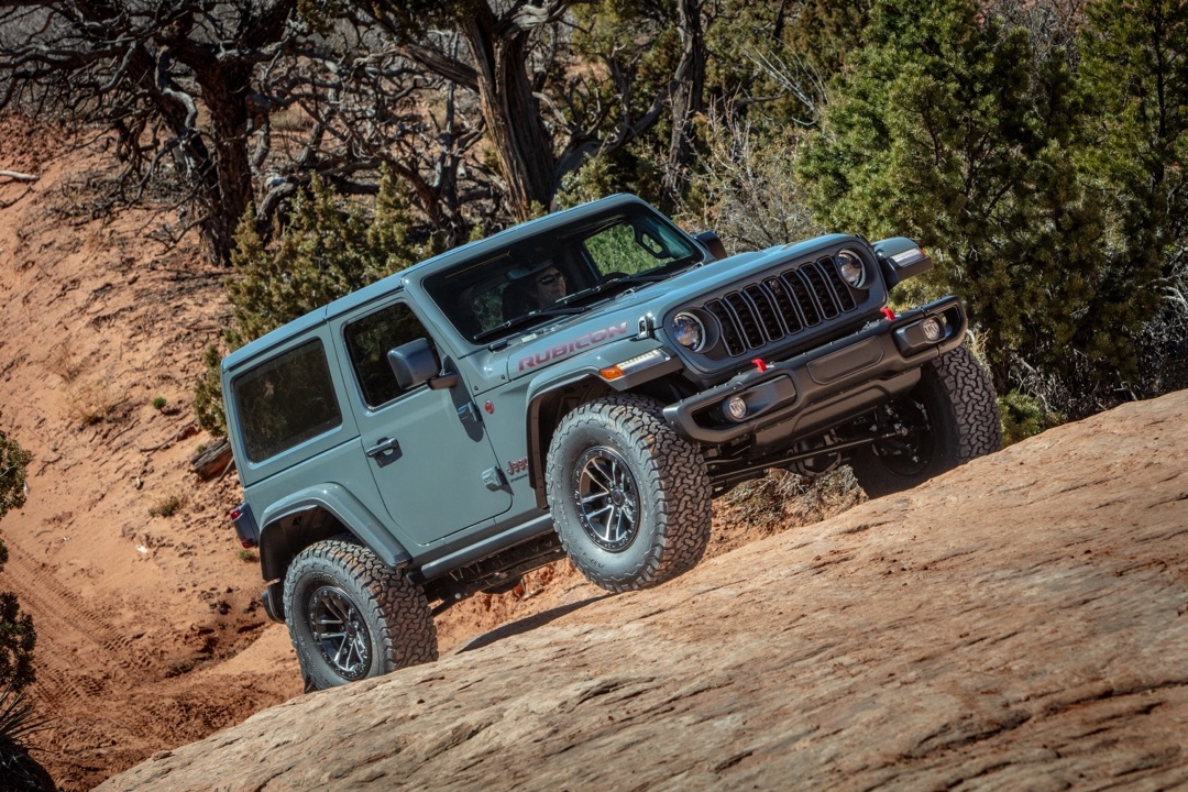 Jeep Wrangler Rubicon 2025 en pleine ascension d’un sentier rocheux dans une forêt aride.