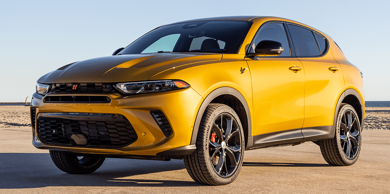 Dodge Hornet GT 2025 jaune vue trois quarts avant, stationné sur une plage au coucher du soleil avec ciel dégagé.