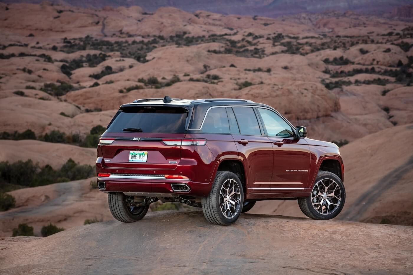 Back 3/4 view of the 2024 Jeep Grand Cherokee parked on a hill in a desert.